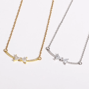 Detailed close-up of bow-knot pendant with sparkling zircons in gold and silver finish