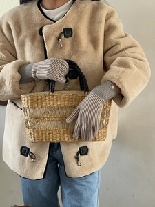 Primer plano de guantes de punto a rayas grises con abrigo beige y botones de cuerno