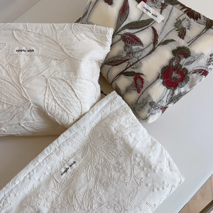 Detail view of cotton pouches with delicate embroidery and 'simple wish' woven label