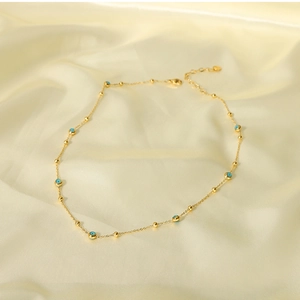Detail view of 18K gold plated necklace with blue turquoise beads on silk fabric