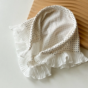 Vue détaillée d'un col en dentelle blanc à pois noirs avec des bords à volants plissés