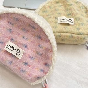 Close-up of shell-shaped plush makeup bags with colorful dots and sheepskin fleece edges