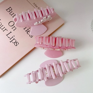 Close-up of pink bow rhinestone hair clips and floral shark clips with glossy finish