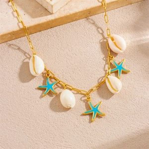 Summer gold necklace with white shells and blue starfish pendants on a stone surface