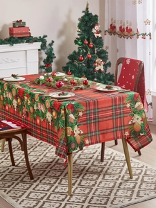 Close-up of festive red plaid tablecloth with pine cones and gingerbread house motifs