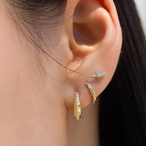 Detail view of gold earrings set featuring geometric diamond studs and beaded hoops