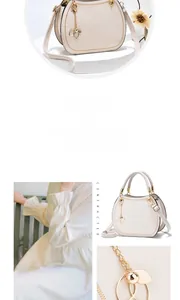 Creamy white handbag detail featuring gold leaf pendant and adjustable shoulder strap