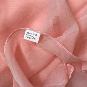 Detailed macro shot of pink silk-feel polyester fabric with 100% material label