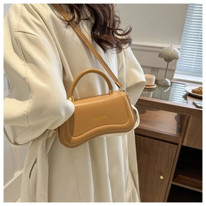 Close-up of caramel brown crescent leather handbag with gold Fashion text detail