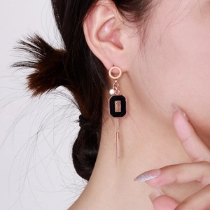 Détail de boucles d'oreilles pampilles en or rose sur modèle avec accents géométriques