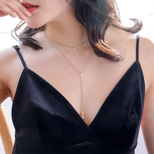 Detail of double-layer gold necklace featuring white pearl and wire-wrapped pink gemstone