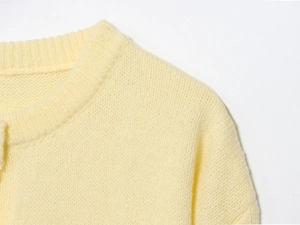 Detail shot of the round neckline and soft texture on this pale yellow knit cardigan