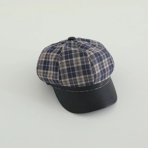 Close-up of checkered newsboy hat with blue plaid fabric and black faux leather brim