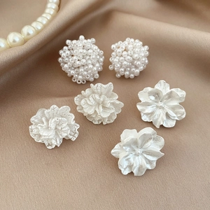 Elegante set di orecchini con perle e fiori su lussuoso tessuto di seta color champagne