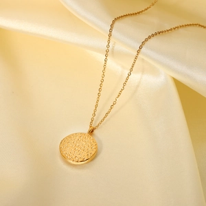 Détail du collier à pendentif texturé en or 18 carats sur fond de soie élégant