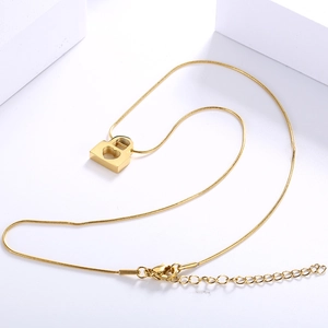 Golden heart-shaped lock pendant necklace with snake chain on white background