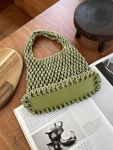 Detail of green woven cotton rope tote bag with reinforced PU leather base on a wooden desk
