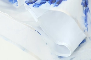 Détail du tissu en mousseline fleurie bleue avec doublure blanche et coutures précises