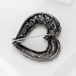 Rear view of heart-shaped vintage brooch showing safety pin clasp and textured metal back