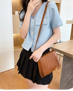 Brown tassel crossbody bag detail on model in a modern cafe setting lifestyle view
