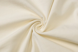 Detailed macro view showing the cream-colored knitted cotton fabric texture and soft drapes