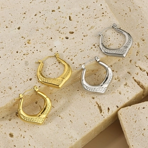 Detailed view of U-shaped gold and silver earrings with textured diamond pattern on stone