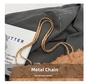 Detail shot of the golden metal chain and woven strap on a vintage brown shoulder bag