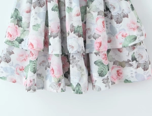 Detail des mehrlagigen Blumenmuster-Saums mit rosa und grünen Mustern auf leichtem Stoff