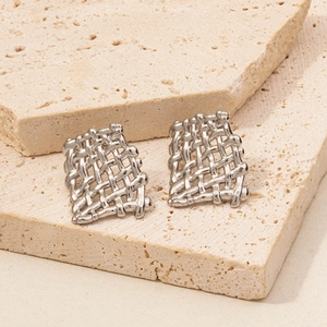 Macro detail of silver rectangular earrings with woven mesh texture on travertine stone