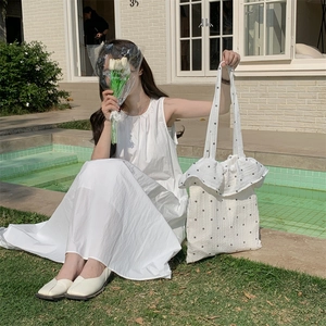 Detail of white canvas tote bag with black floral print and stylish ruffled edges