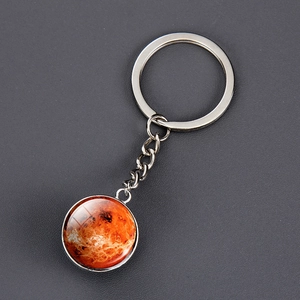 Macro view of solar system planet keychain with orange Mars glass dome on grey background
