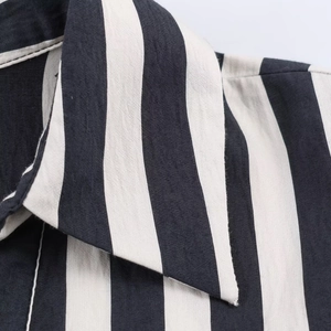 Detailed macro view of the shirt collar featuring classic black and white vertical stripes