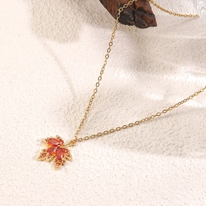 Macro shot of gold maple leaf pendant with gradient orange stones on fine gold metal chain