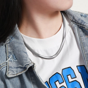 Close-up of a sleek silver flat snake chain necklace worn on a person neck