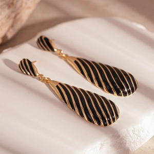 Macro view of vintage black enamel teardrop earrings with elegant golden zebra stripes