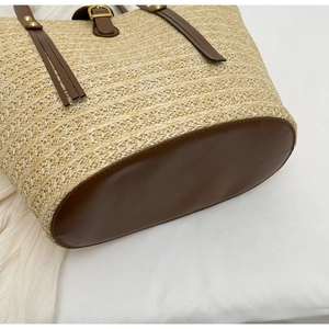 Close-up of woven straw texture and brown leather bottom with golden metallic rivets
