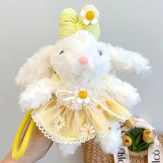 Detail shot of a plush bunny keychain wearing a daisy lace dress and matching bow