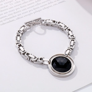 Macro detail of silver stainless steel chain with large faceted black stone and OT clasp