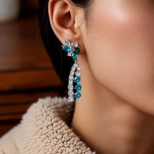 Close-up of vintage flower earrings with blue and green crystals and long silver tassels