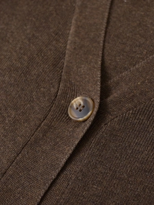 Detail of dark brown knit cardigan with V-neck and amber textured button closure