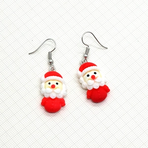 Close-up of cute cartoon Santa Claus resin earrings with festive red and white details
