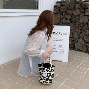 Detail of leopard print canvas tote bag with brand label shown in a street style setting
