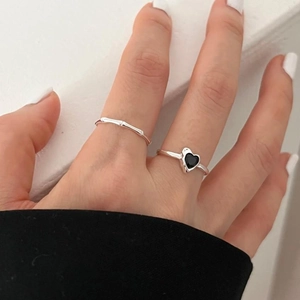 Detail of silver bamboo textured ring and black heart stone ring worn on finger