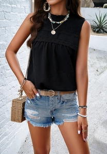 Detail of a chic black sleeveless polka dot chiffon top paired with casual denim shorts