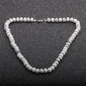 Detail shot of the white natural stone abacus beads and metallic clasp on black texture
