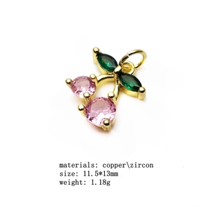 Macro detail of cherry charm with pink zircon stones and green leaf on gold copper base