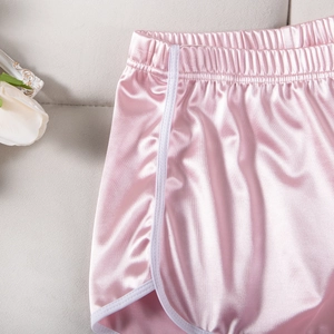 Detail of pink satin yoga shorts featuring elastic waistband and white contrast piping