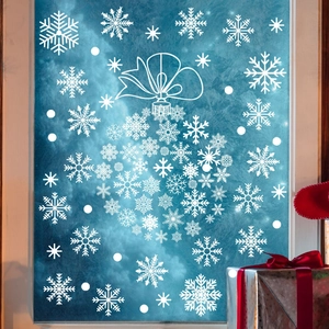 Close-up of white snowflake window stickers with large ornaments on frosted glass