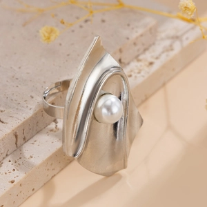 Artistic silver pleated metal ring with a large pearl on a natural stone background