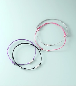 Macro shot of minimalist s925 silver thread bracelets in black, purple, pink, and grey